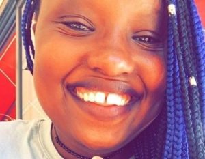 Kavana Wa Kilele smiles. She is Black with multicolour braids.