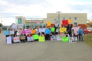 A group of 15-20 people hold homemade signs with pro-choice slogans.